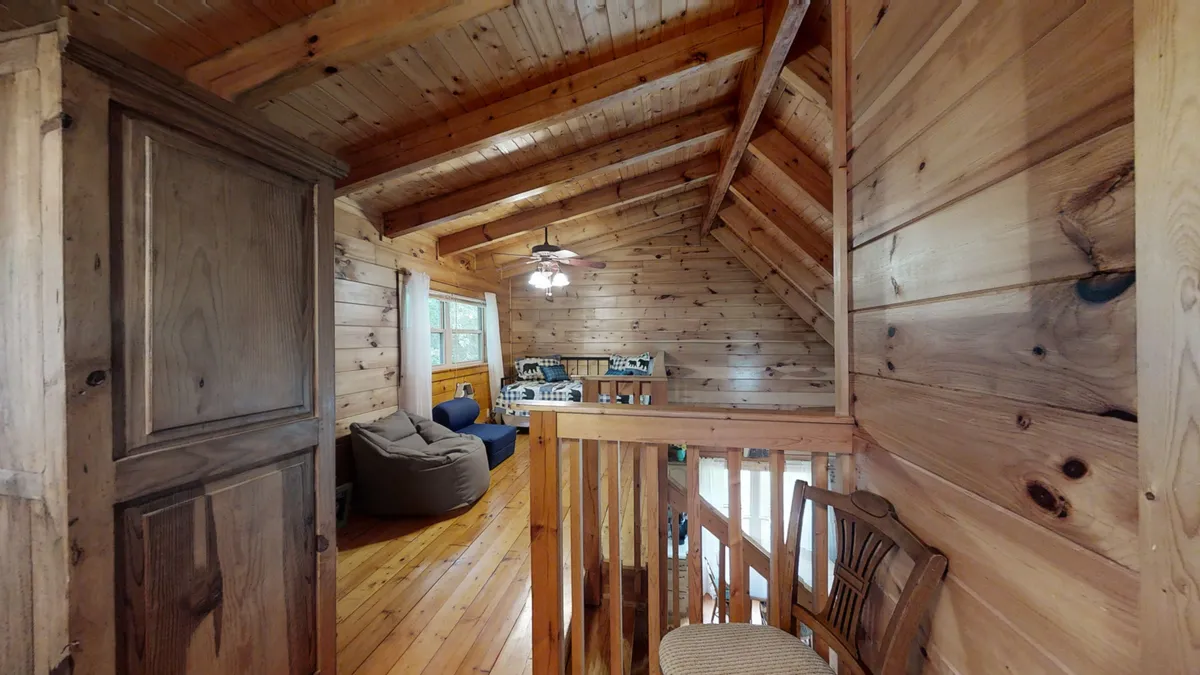 This image presents a comfortable seating area framed by wooden beams and a pocket door, designed for relaxation, socializing, or enjoying downtime together. The open layout and welcoming mood evoke a shared family and pet experience.