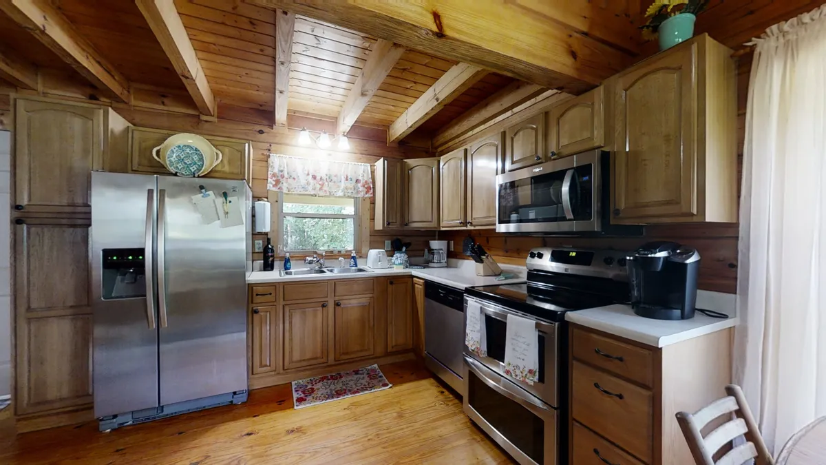 A cozy kitchen scene featuring stainless steel appliances, wooden cabinets, floral curtains, and a spacious kitchen island. The setup encourages family meal prep and shared moments, with enough space for cooking together and gathering around the kitchen island.